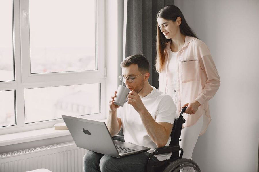 Begeleider en cliënt werken samen achter een laptop.